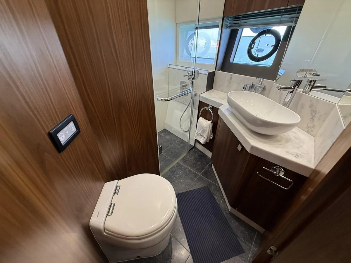 A modern yacht bathroom featuring a sleek design with wooden accents and a glass-enclosed shower. aboard "BISHWISH" Yacht for Sale