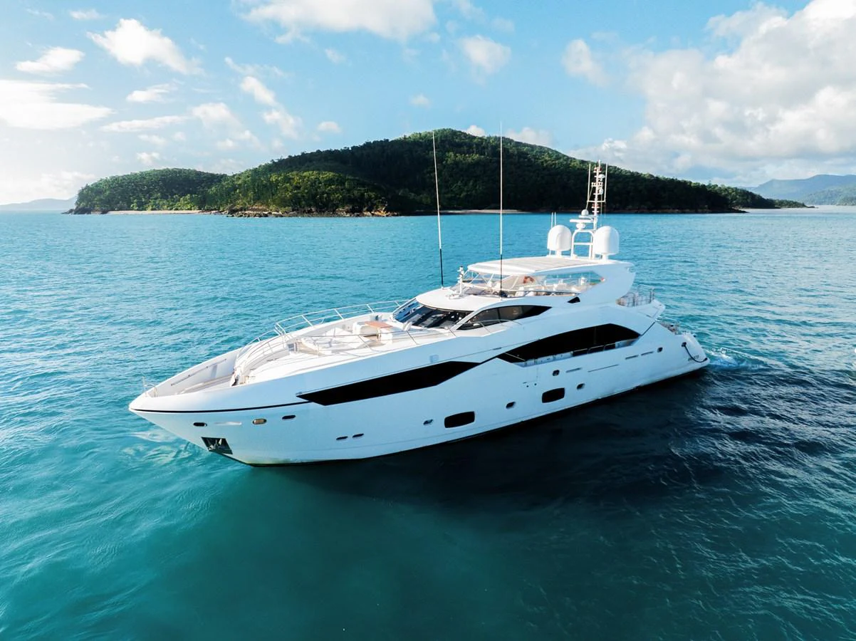 A sleek and modern yacht glides gracefully on calm blue waters with a scenic island backdrop. aboard RASCAL Yacht for Sale