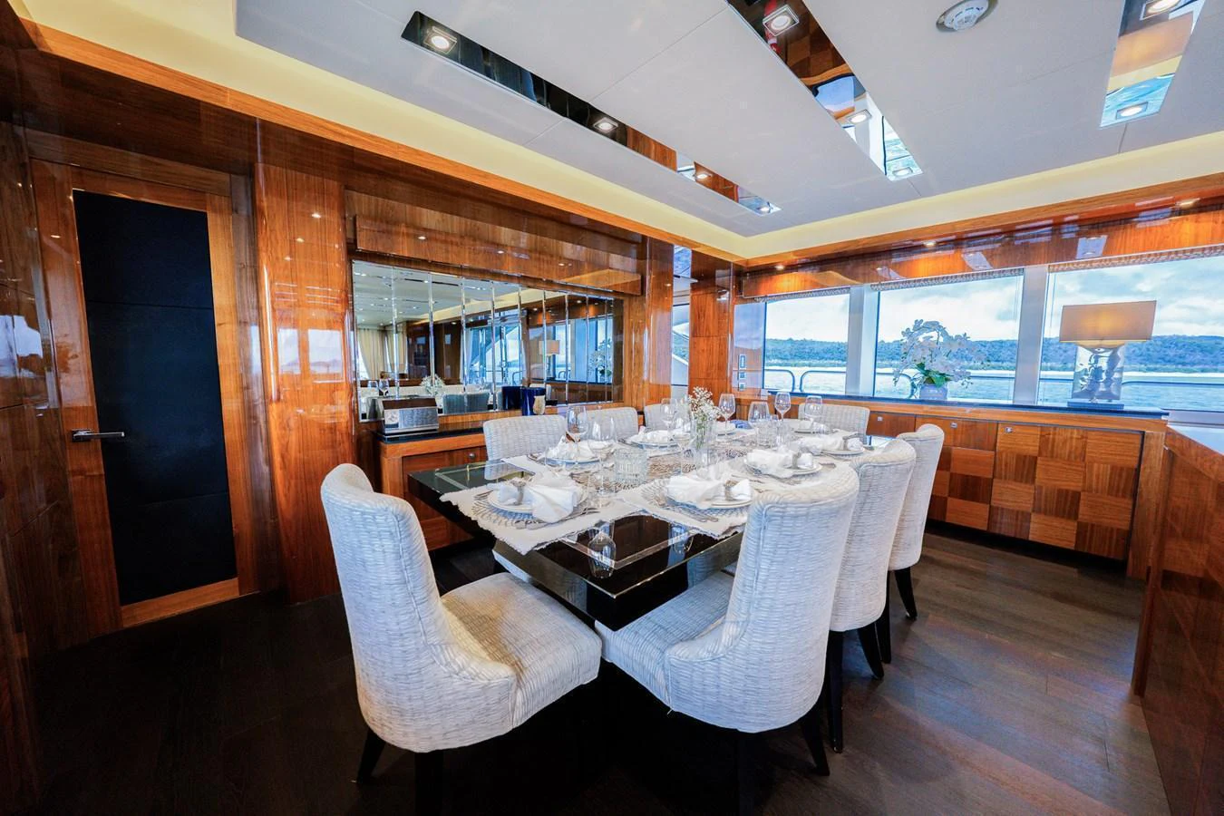 The yacht's dining area features a luxurious table setting with a stunning view through large windows. aboard RASCAL Yacht for Sale