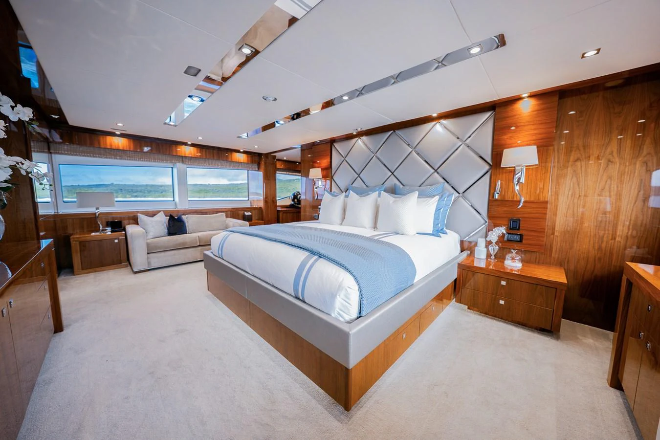 The master stateroom features a luxurious bed with elegant wood paneling and ample natural light. aboard RASCAL Yacht for Sale