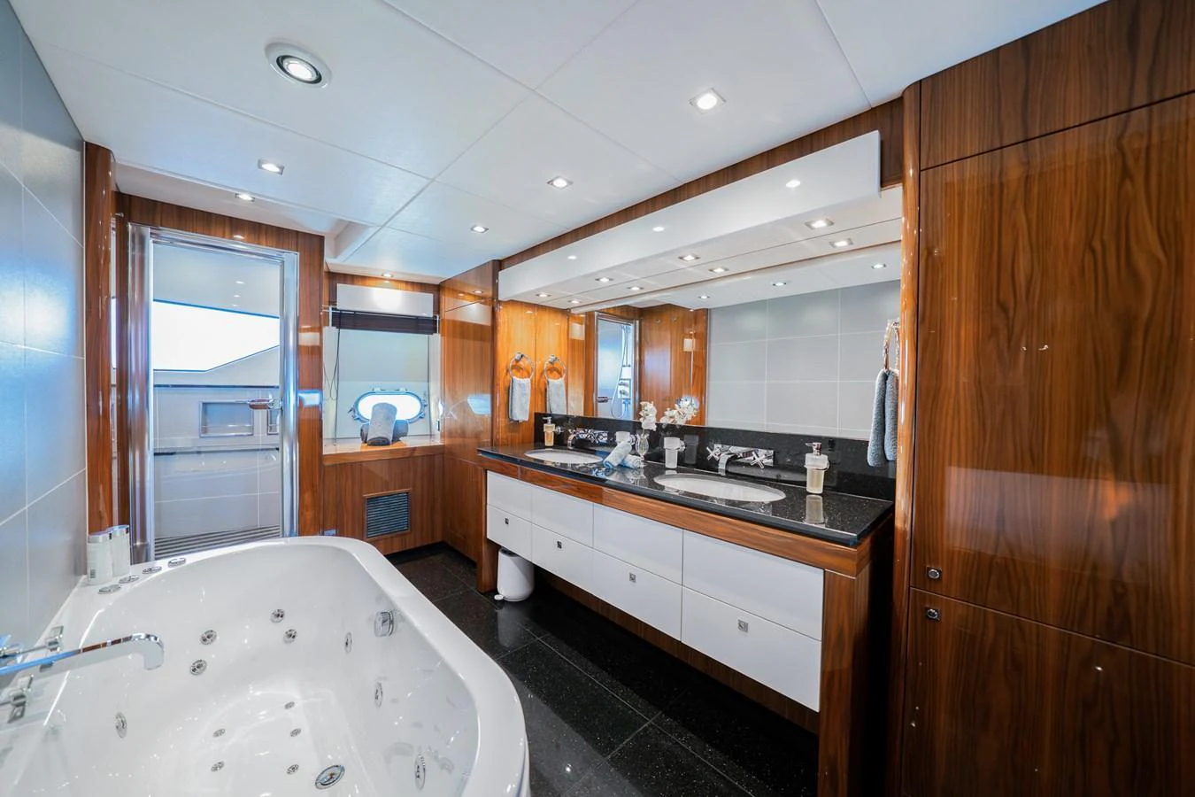 The yacht's bathroom features a luxurious jacuzzi tub and dual sinks with elegant wood paneling. aboard RASCAL Yacht for Sale