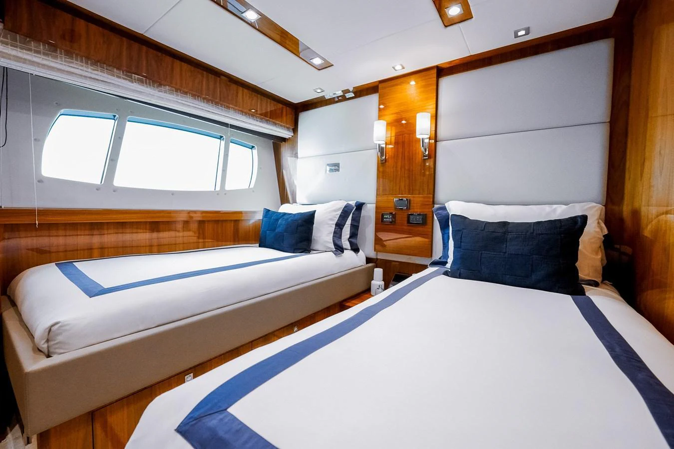 The guest stateroom features twin beds with elegant bedding and ample natural light from the windows. aboard RASCAL Yacht for Sale