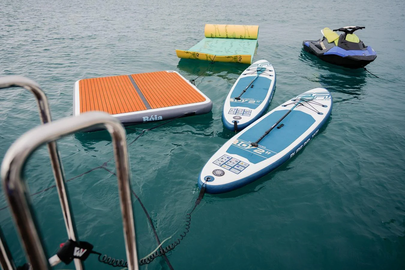 A selection of water toys including paddleboards, a floating mat, and a jet ski are ready for fun on the water. aboard RASCAL Yacht for Sale