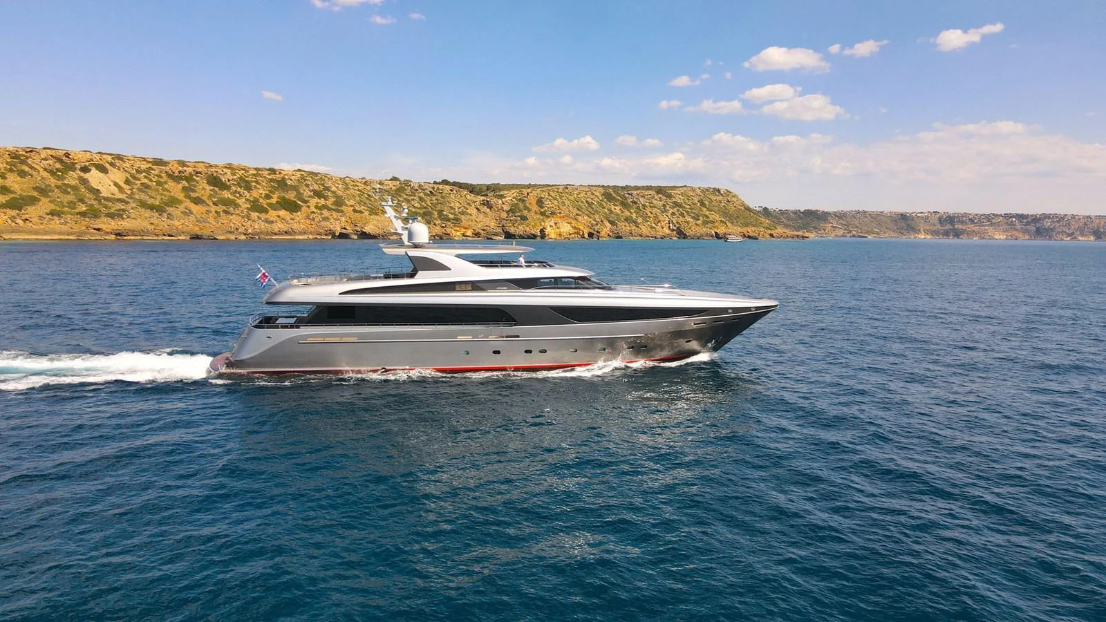 A sleek and modern yacht cruises through calm blue waters with a scenic coastline in the background. aboard SMOOTH OPERATOR Yacht for Sale
