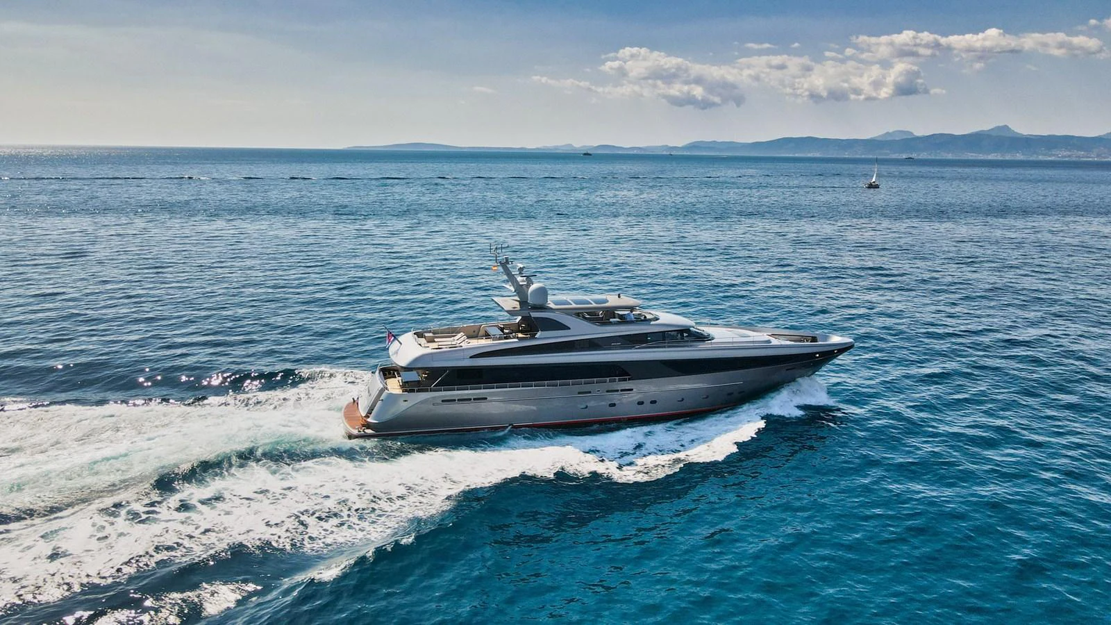 A sleek yacht cruises through clear blue waters with a stunning backdrop of distant mountains. aboard SMOOTH OPERATOR Yacht for Sale