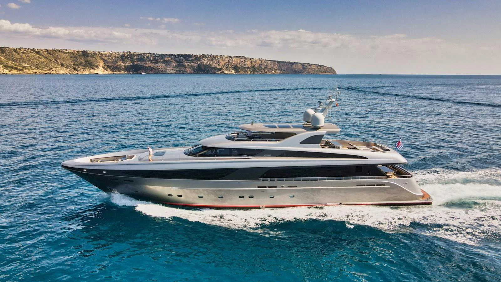 A sleek and modern yacht cruises through clear blue waters with a scenic coastline in the background. aboard SMOOTH OPERATOR Yacht for Sale