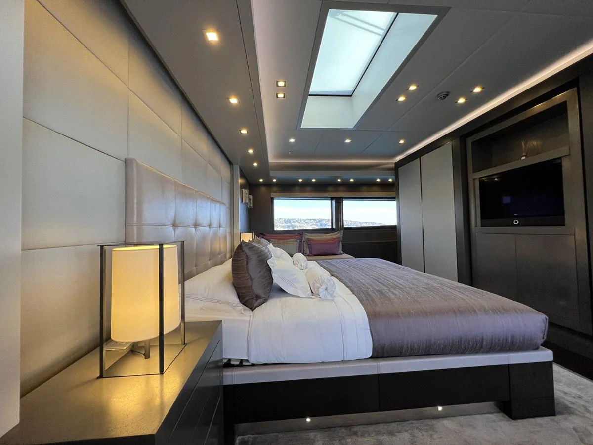 The master stateroom features a luxurious bed with modern lighting and a skylight for natural illumination. aboard SMOOTH OPERATOR Yacht for Sale