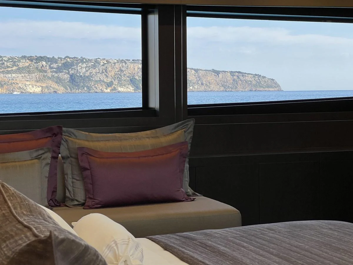 A serene stateroom with a picturesque view of the coastline through large windows. aboard SMOOTH OPERATOR Yacht for Sale
