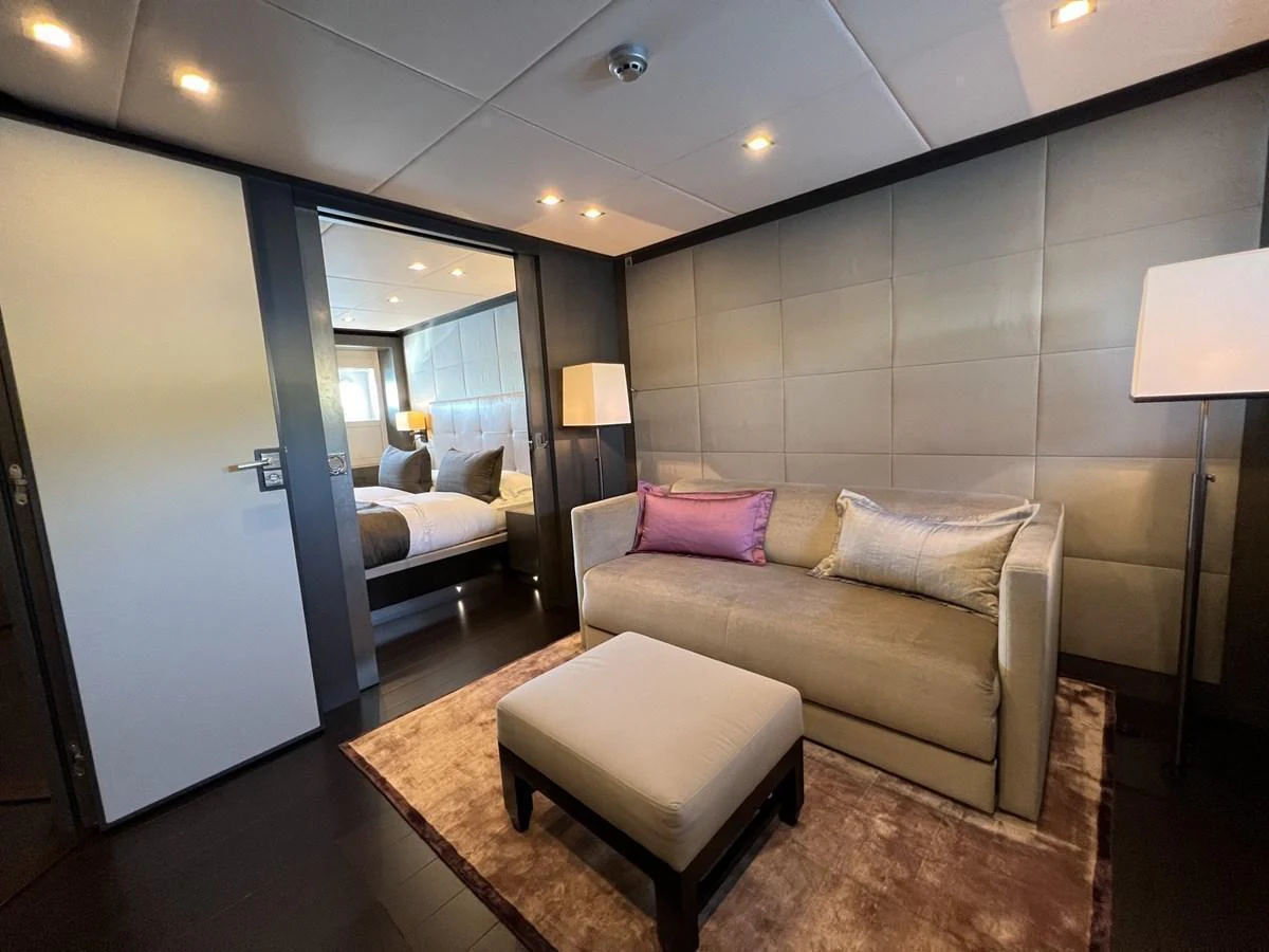 The yacht's stateroom features a cozy seating area with a plush sofa and ottoman, leading into a comfortable sleeping space. aboard SMOOTH OPERATOR Yacht for Sale