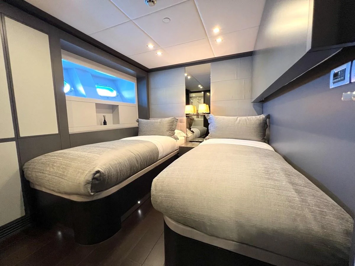 The twin stateroom features two comfortable single beds with modern decor and soft lighting. aboard SMOOTH OPERATOR Yacht for Sale