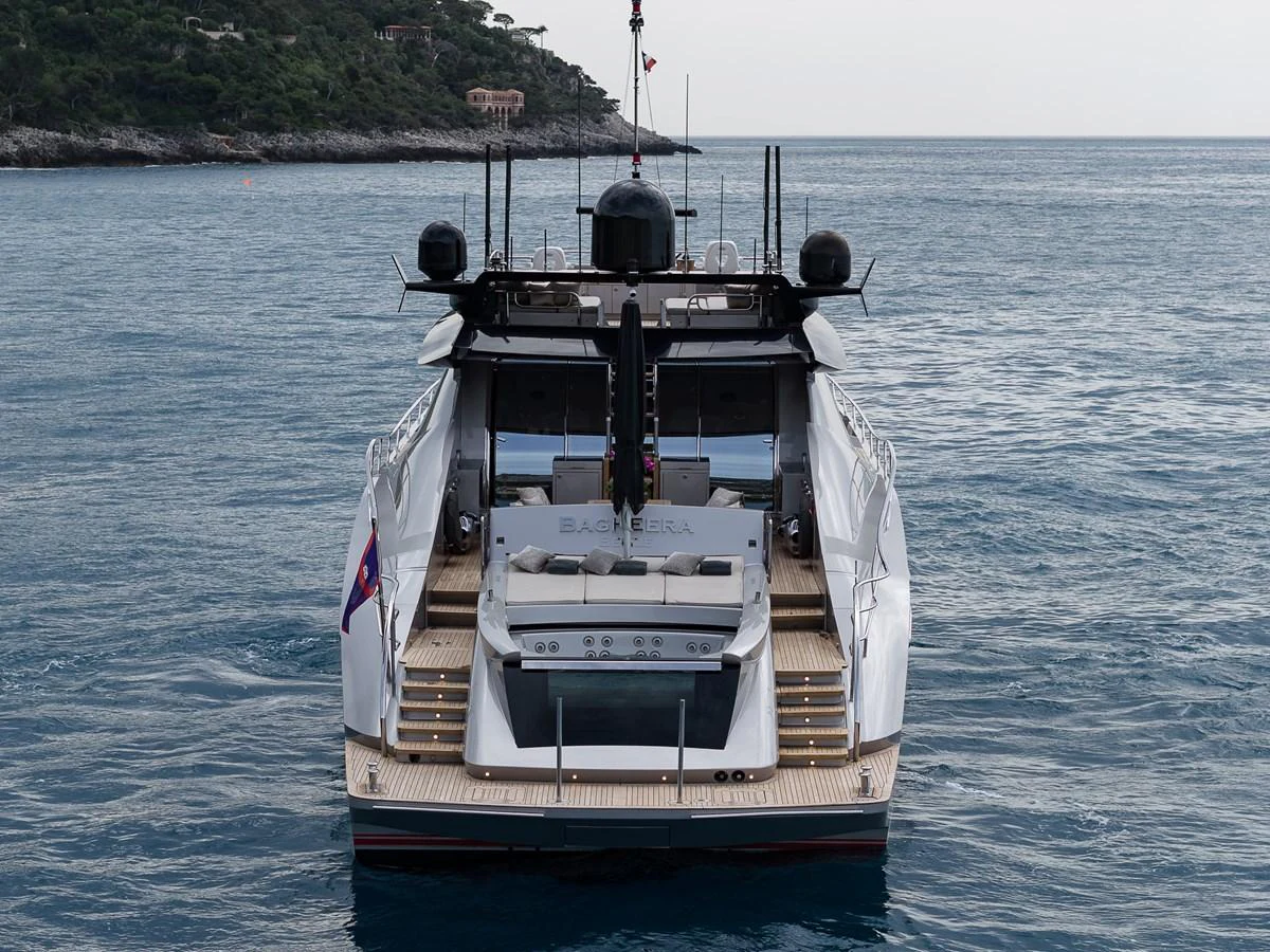 A sleek and modern yacht is anchored in calm waters with a scenic coastline in the background. aboard BAGHEERA Yacht for Sale