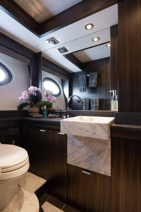 The yacht's bathroom features elegant dark wood finishes and a stylish marble sink. aboard BAGHEERA Yacht for Sale