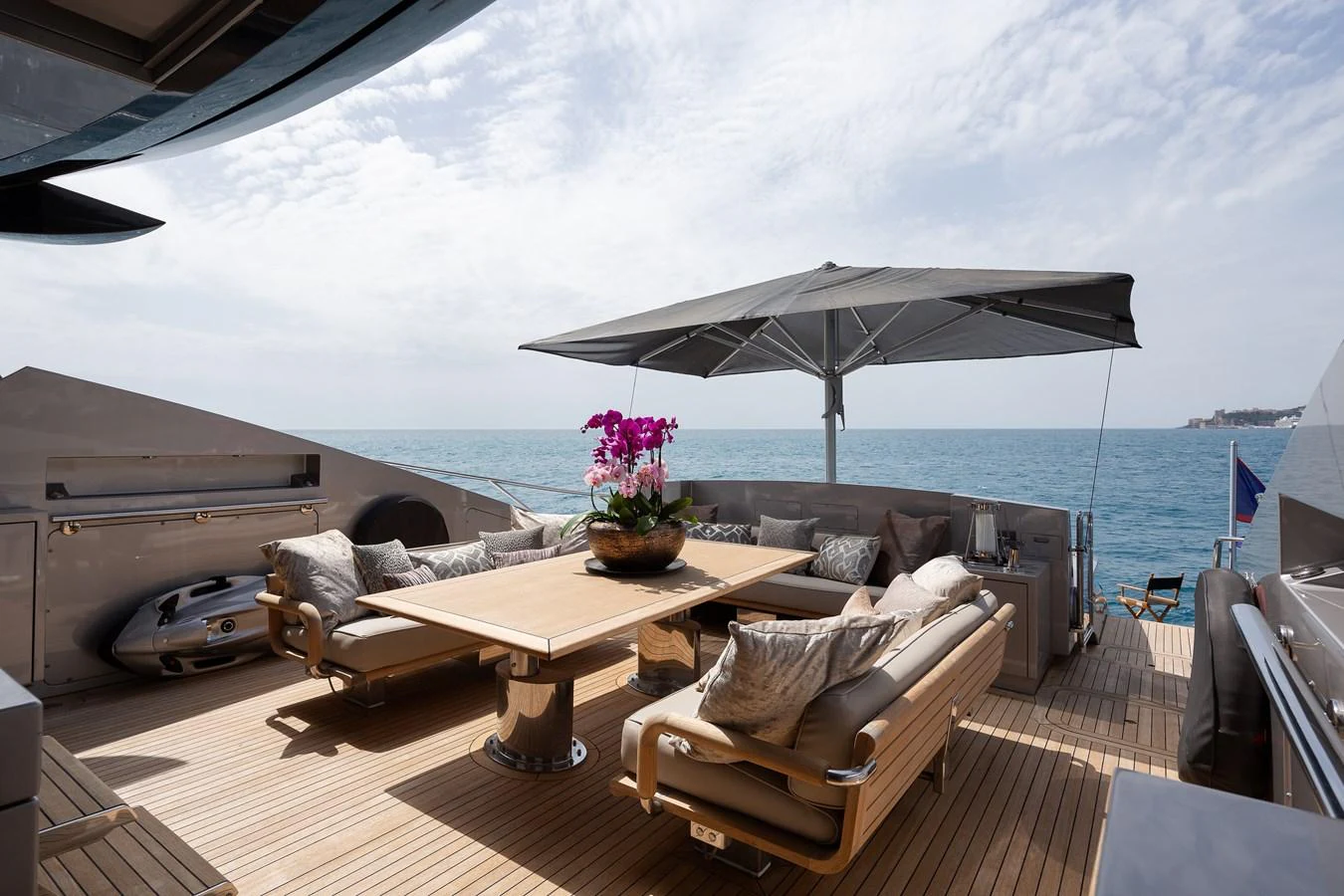 The aft deck features a stylish outdoor dining area with comfortable seating and a large parasol, perfect for enjoying meals with a sea view. aboard BAGHEERA Yacht for Sale
