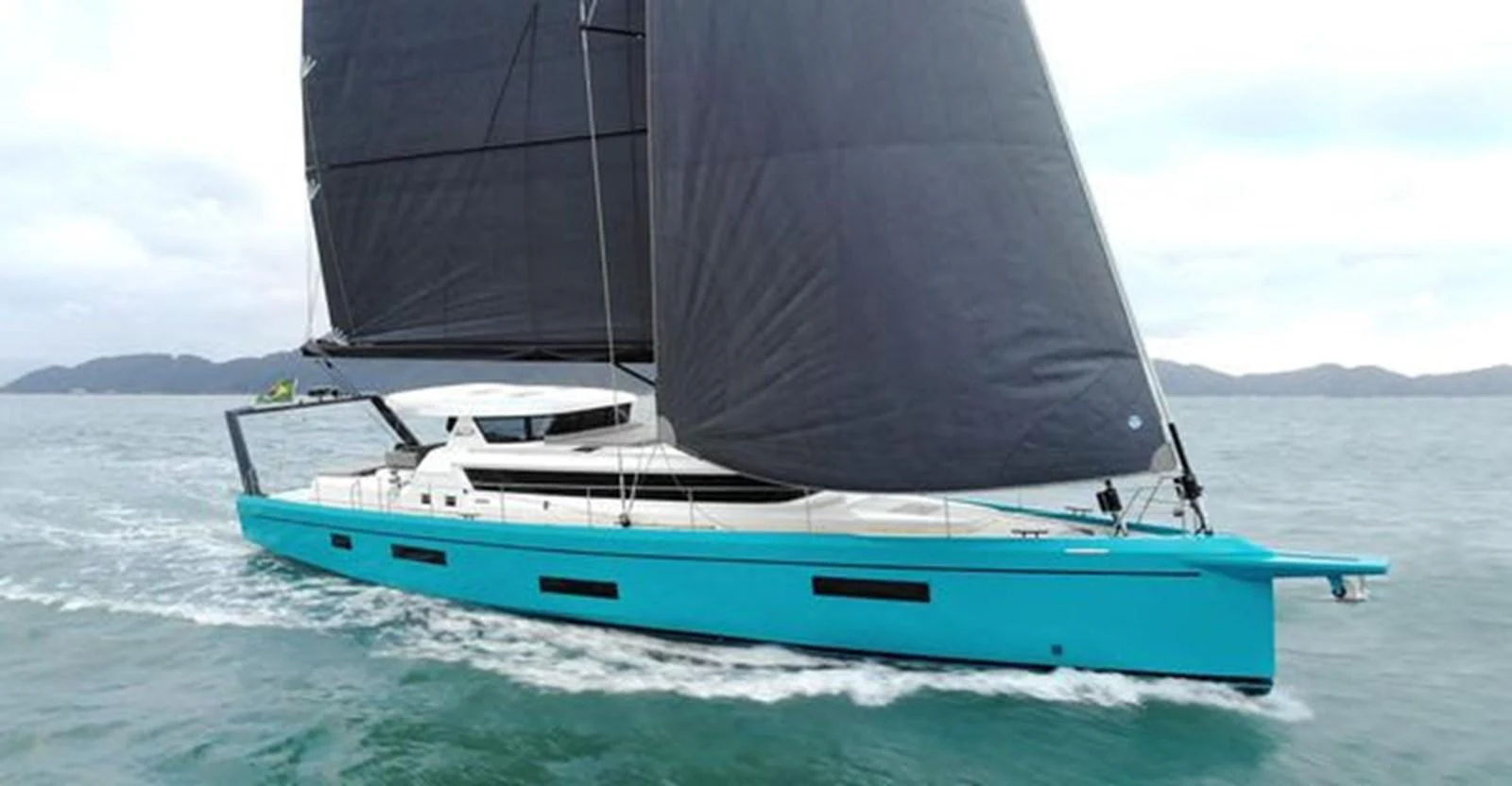 A sleek, modern sailing yacht with turquoise hull and black sails glides through calm waters. aboard 2025 MCP GLOBAL EXP 68 Yacht for Sale