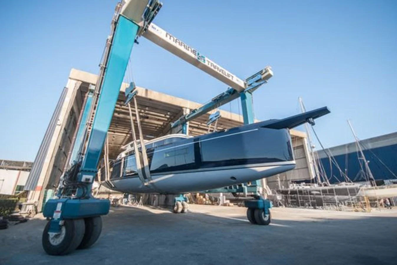 The yacht is being lifted out of the water by a large boat lift in a shipyard. aboard 2025 MCP GLOBAL EXP 68 Yacht for Sale