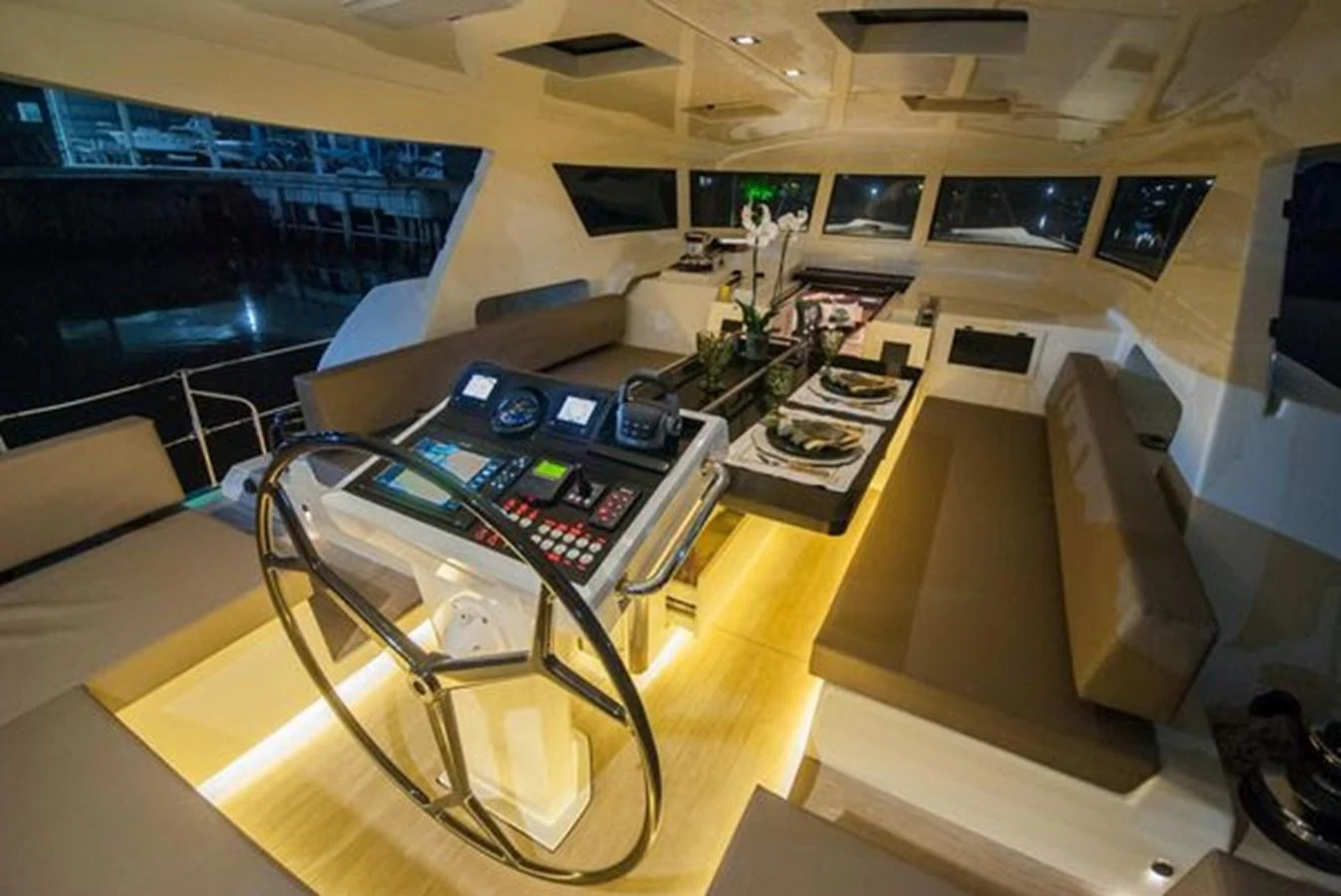 The yacht's helm features a sophisticated control panel and a stylish dining area with ambient lighting. aboard 2025 MCP GLOBAL EXP 68 Yacht for Sale