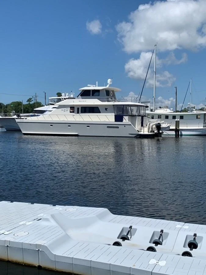 A sleek yacht is docked at a marina under a clear blue sky. aboard THE CAT FROM THE HAT Yacht for Sale