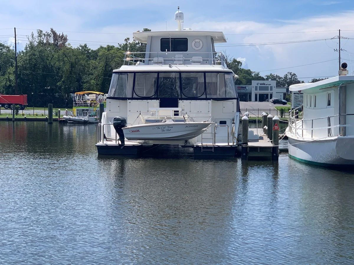 A yacht is docked at a marina, with a small tender attached to its stern. aboard THE CAT FROM THE HAT Yacht for Sale