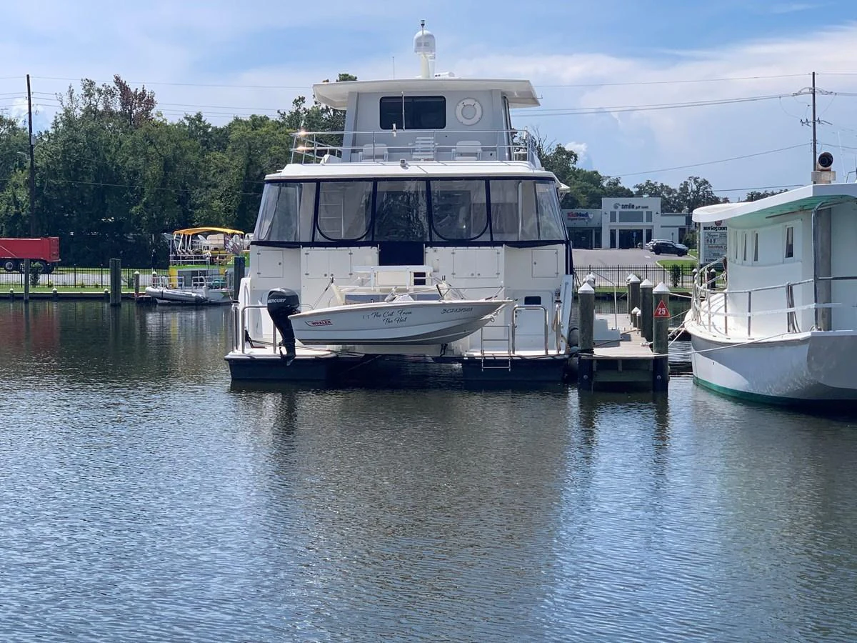 A yacht is docked at a marina, showcasing its stern and a small tender boat attached. aboard THE CAT FROM THE HAT Yacht for Sale