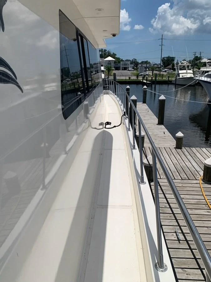 The side deck of the yacht offers a sleek passage with stainless steel railings and a view of the marina. aboard THE CAT FROM THE HAT Yacht for Sale