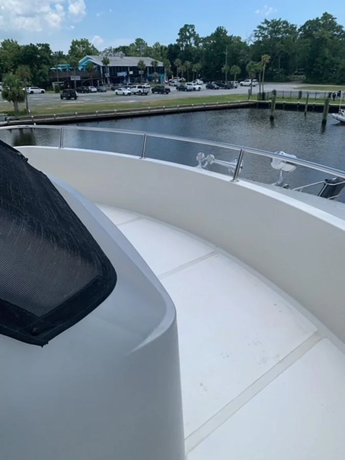 The yacht's exterior deck offers a serene view of the marina and surrounding greenery. aboard THE CAT FROM THE HAT Yacht for Sale