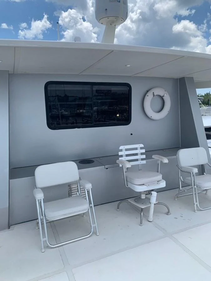The yacht's exterior features a shaded seating area with comfortable chairs and a life ring for safety. aboard THE CAT FROM THE HAT Yacht for Sale