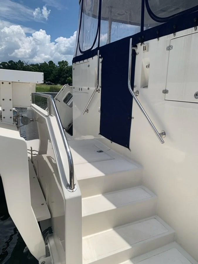 A close-up view of the yacht's exterior stairs leading to an upper deck, featuring stainless steel handrails and a navy blue canvas cover. aboard THE CAT FROM THE HAT Yacht for Sale