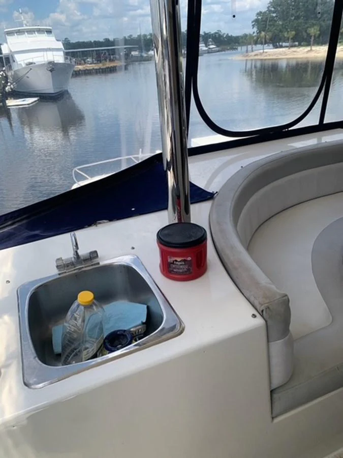A close-up view of a yacht's seating area with a small sink and cleaning supplies. aboard THE CAT FROM THE HAT Yacht for Sale