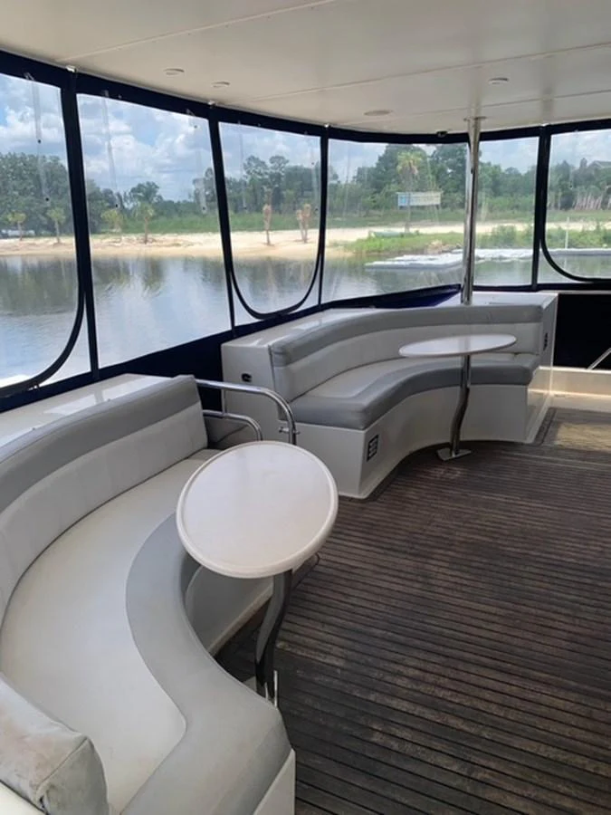 The yacht's salon features curved seating with tables, offering a comfortable and scenic space for relaxation. aboard THE CAT FROM THE HAT Yacht for Sale