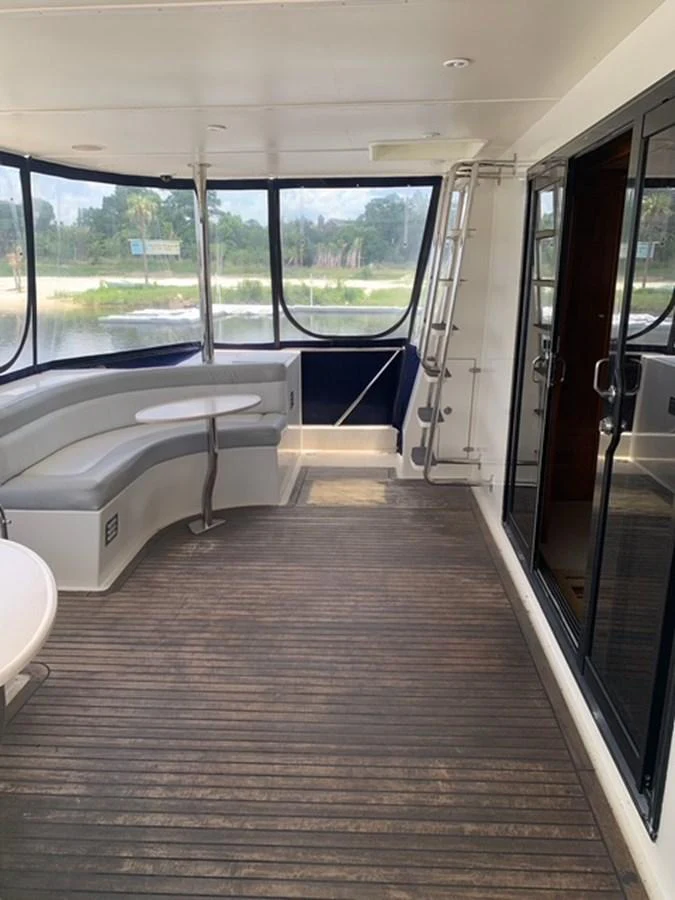 The aft deck features a comfortable seating area with a table and large windows offering scenic views. aboard THE CAT FROM THE HAT Yacht for Sale