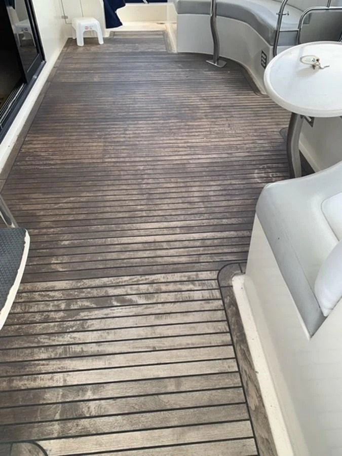 The aft deck features a spacious seating area with a wooden floor and a small table. aboard THE CAT FROM THE HAT Yacht for Sale