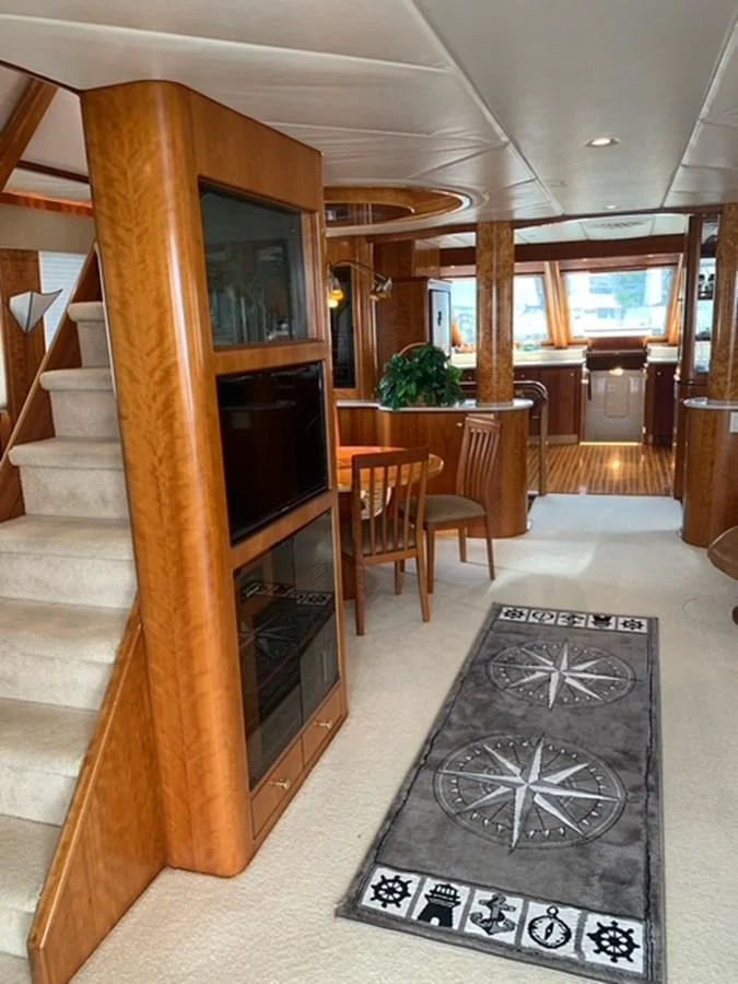 The yacht's salon features warm wood finishes, a cozy dining area, and a staircase leading to the upper deck. aboard THE CAT FROM THE HAT Yacht for Sale