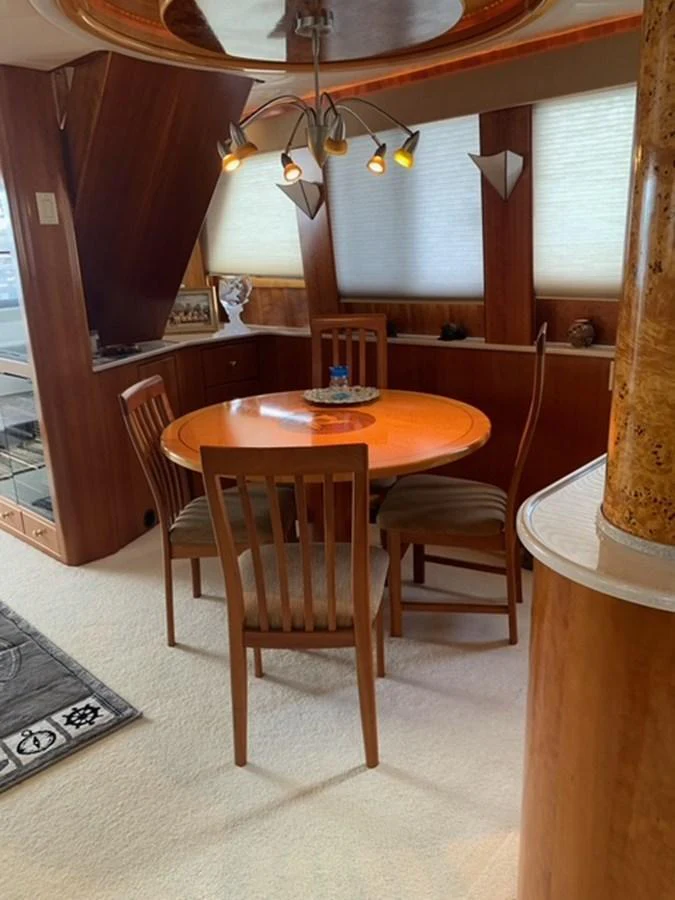 The yacht's dining area features a cozy round table with wooden chairs and warm lighting. aboard THE CAT FROM THE HAT Yacht for Sale