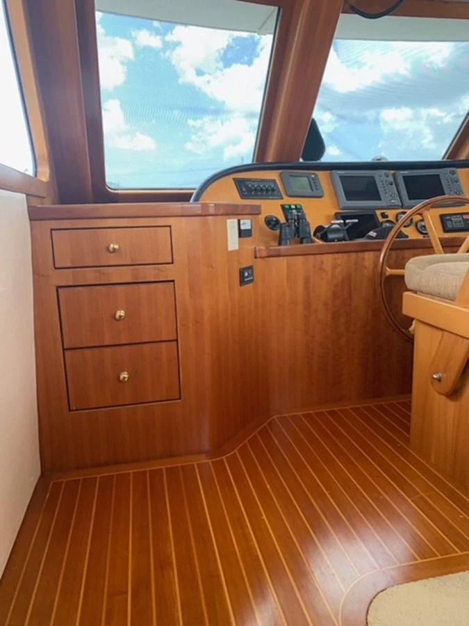 The helm station features rich wooden cabinetry and advanced navigation equipment. aboard THE CAT FROM THE HAT Yacht for Sale
