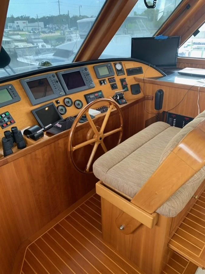 The helm station features a classic wooden steering wheel and an array of navigational instruments. aboard THE CAT FROM THE HAT Yacht for Sale