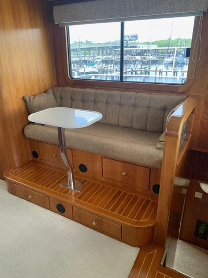The cozy salon features a comfortable built-in seating area with a small table, perfect for relaxation or casual dining. aboard THE CAT FROM THE HAT Yacht for Sale