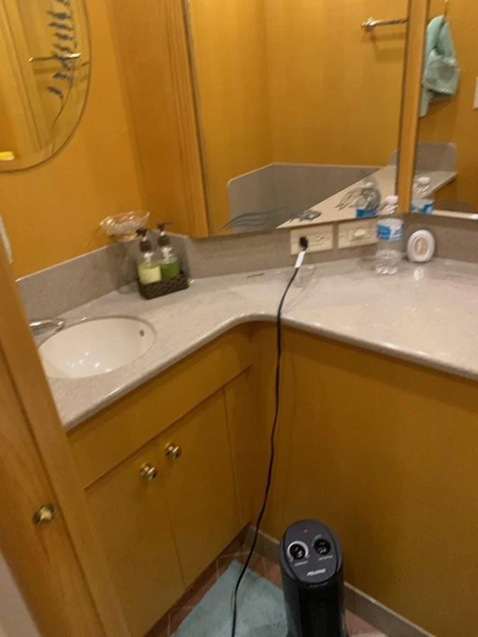 A compact yacht bathroom with a sink, mirror, and toiletries. aboard THE CAT FROM THE HAT Yacht for Sale