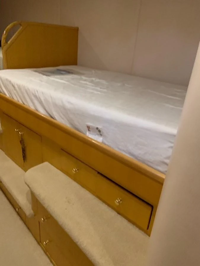 A cozy stateroom featuring a single bed with wooden cabinetry below. aboard THE CAT FROM THE HAT Yacht for Sale