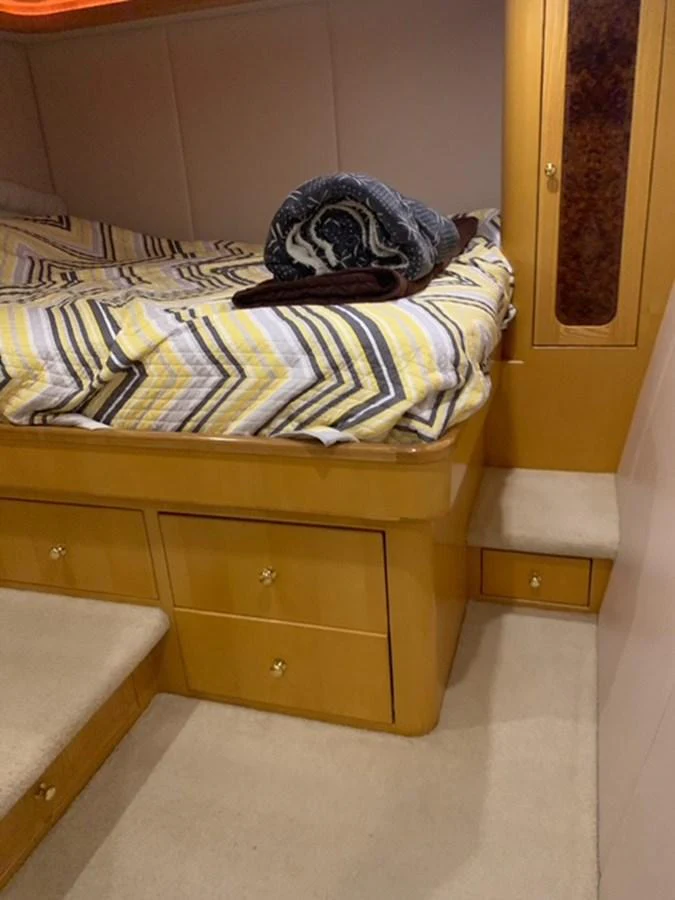 A cozy stateroom with a neatly made bed and wooden cabinetry. aboard THE CAT FROM THE HAT Yacht for Sale