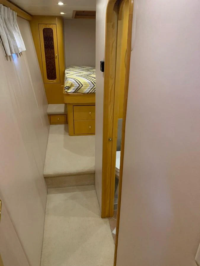 A cozy yacht cabin featuring a bed with patterned bedding and wooden cabinetry. aboard THE CAT FROM THE HAT Yacht for Sale