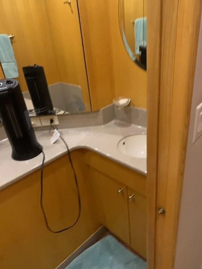 The image shows a compact bathroom with wooden cabinetry and a small sink area. aboard THE CAT FROM THE HAT Yacht for Sale