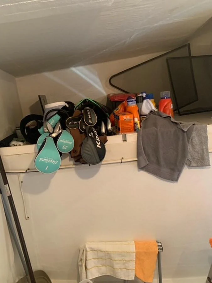 A storage area with various items including golf clubs, cleaning supplies, and clothing. aboard THE CAT FROM THE HAT Yacht for Sale