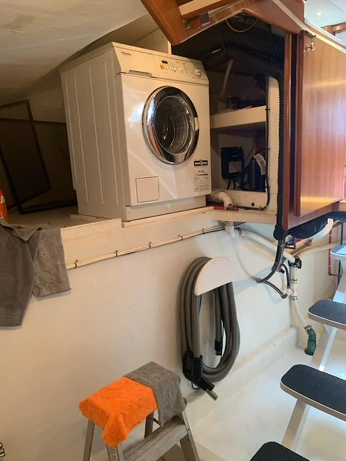 A practical laundry area on the yacht featuring a washing machine and storage space. aboard THE CAT FROM THE HAT Yacht for Sale