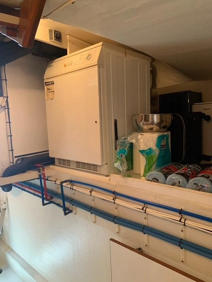 The image shows a compact laundry area with a washing machine and various supplies. aboard THE CAT FROM THE HAT Yacht for Sale