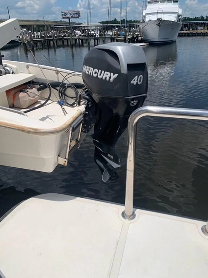 The image showcases the stern of a yacht with a Mercury 40 outboard motor, docked at a marina. aboard THE CAT FROM THE HAT Yacht for Sale
