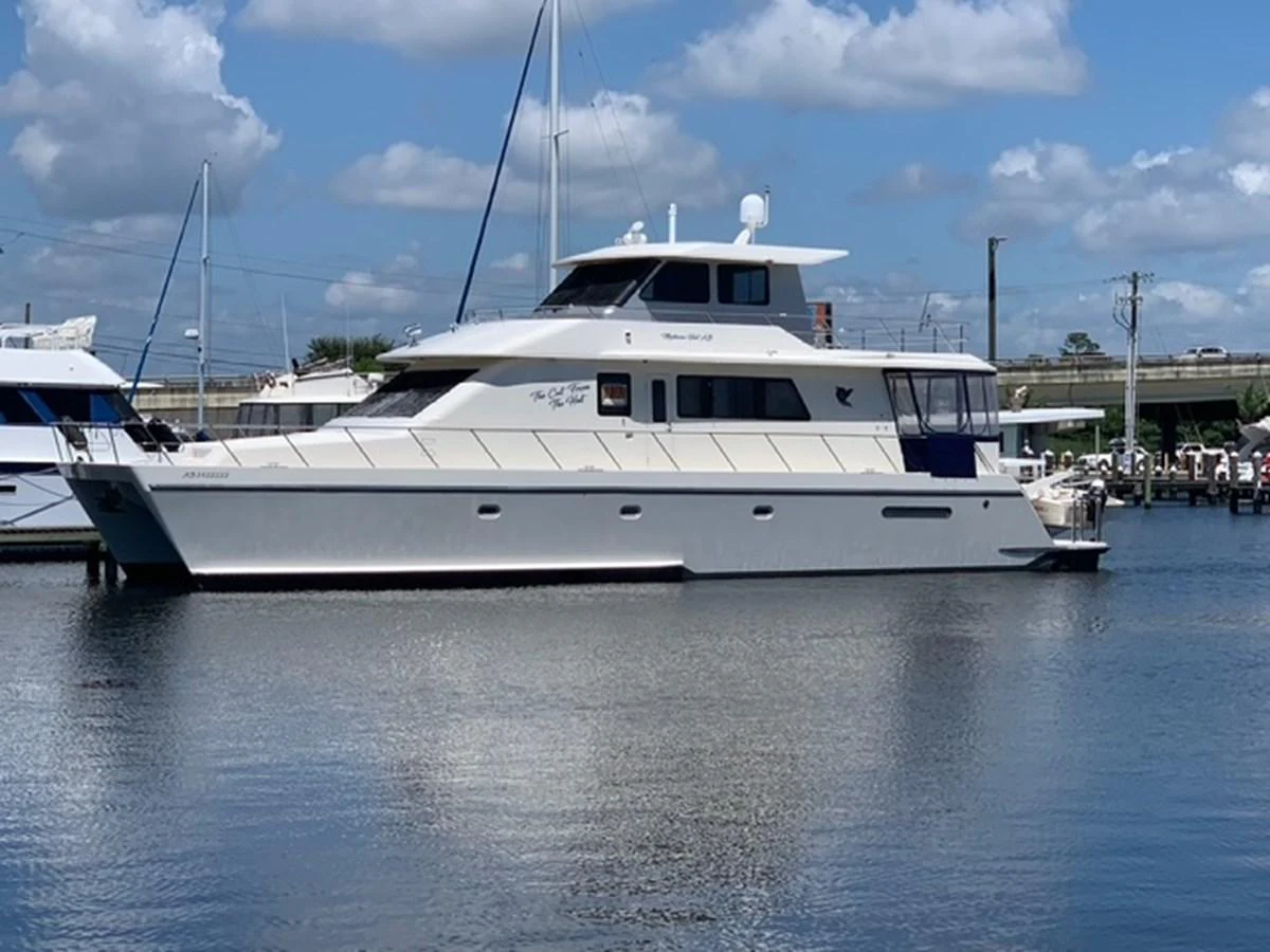 A sleek yacht is docked in a serene marina under a bright blue sky with scattered clouds. aboard THE CAT FROM THE HAT Yacht for Sale
