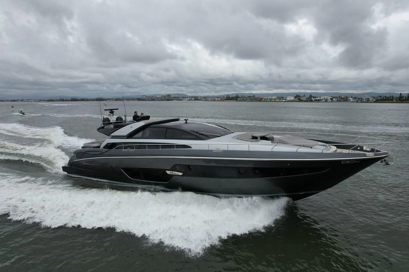 A sleek, modern yacht cruises through the water under a cloudy sky. aboard EVENFLOW Yacht for Sale