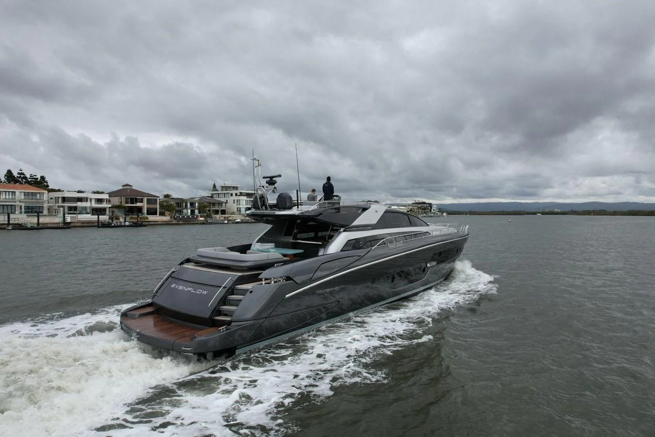 A sleek, modern yacht cruises through calm waters under a cloudy sky. aboard EVENFLOW Yacht for Sale