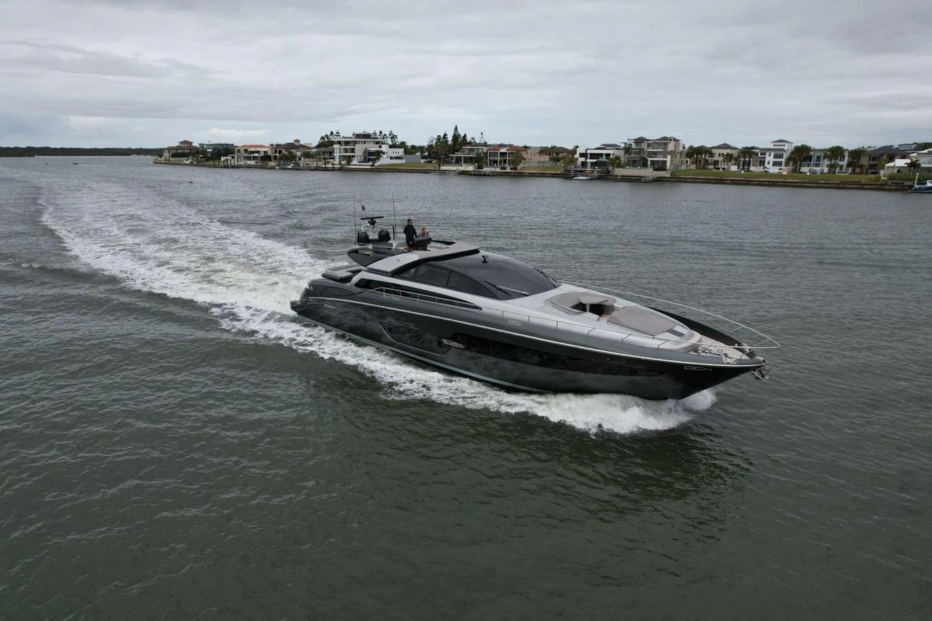 A sleek, modern yacht cruises through calm waters near a coastal town. aboard EVENFLOW Yacht for Sale