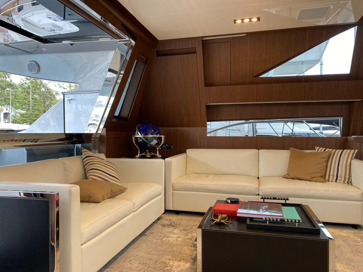 The yacht's interior features a luxurious seating area with plush white sofas and elegant wooden paneling. aboard EVENFLOW Yacht for Sale